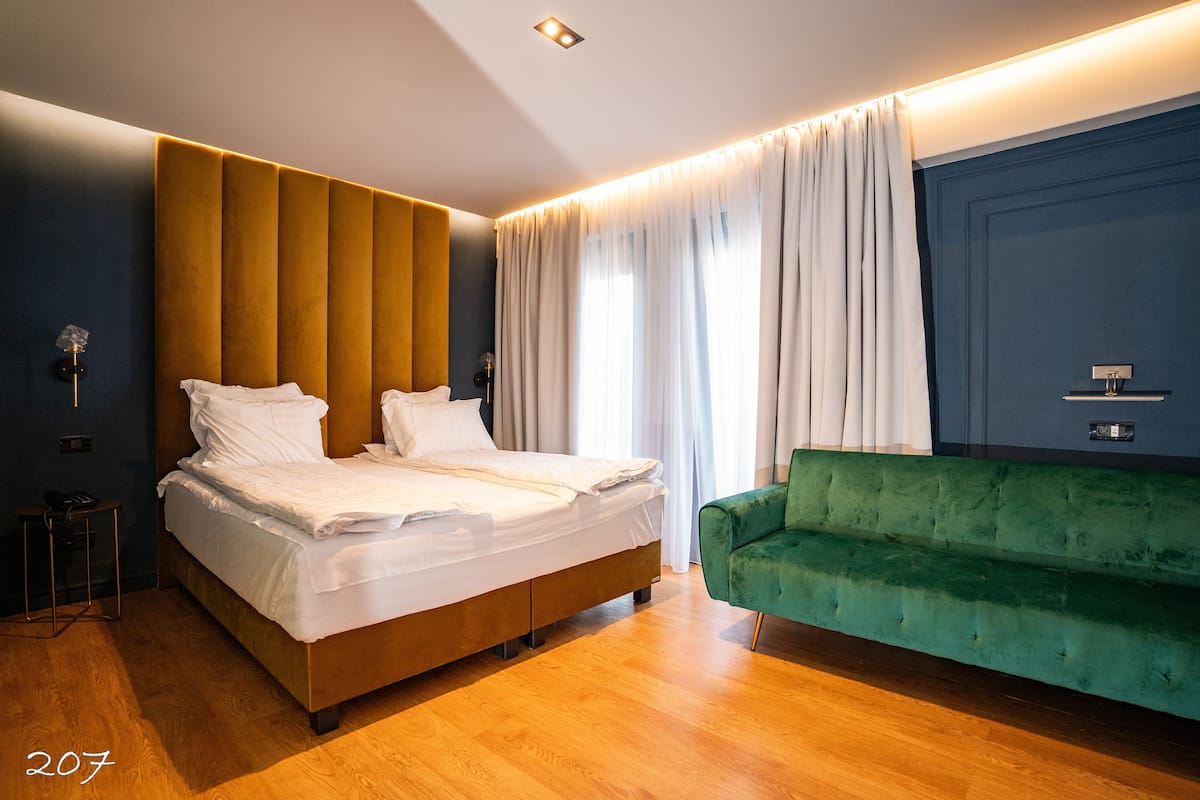Ein modernes Schlafzimmer mit einem großen Bett, einem grünen Sofa und einer blauen Akzentwand.