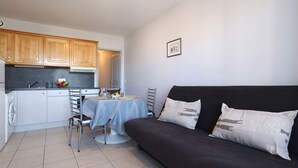 Un espacio habitable compacto con kitchenette, una mesa de comedor y un sofá.