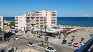 Un hotel de varios pisos con balcones, una zona de estacionamiento y vistas a la playa y al mar.