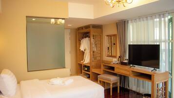 Una habitación de hotel con una cama grande, un escritorio con televisor, un armario y un espejo.