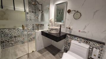 Ein Badezimmer mit Duschkabine aus Glas, Marmorwaschbecken und Toilette.