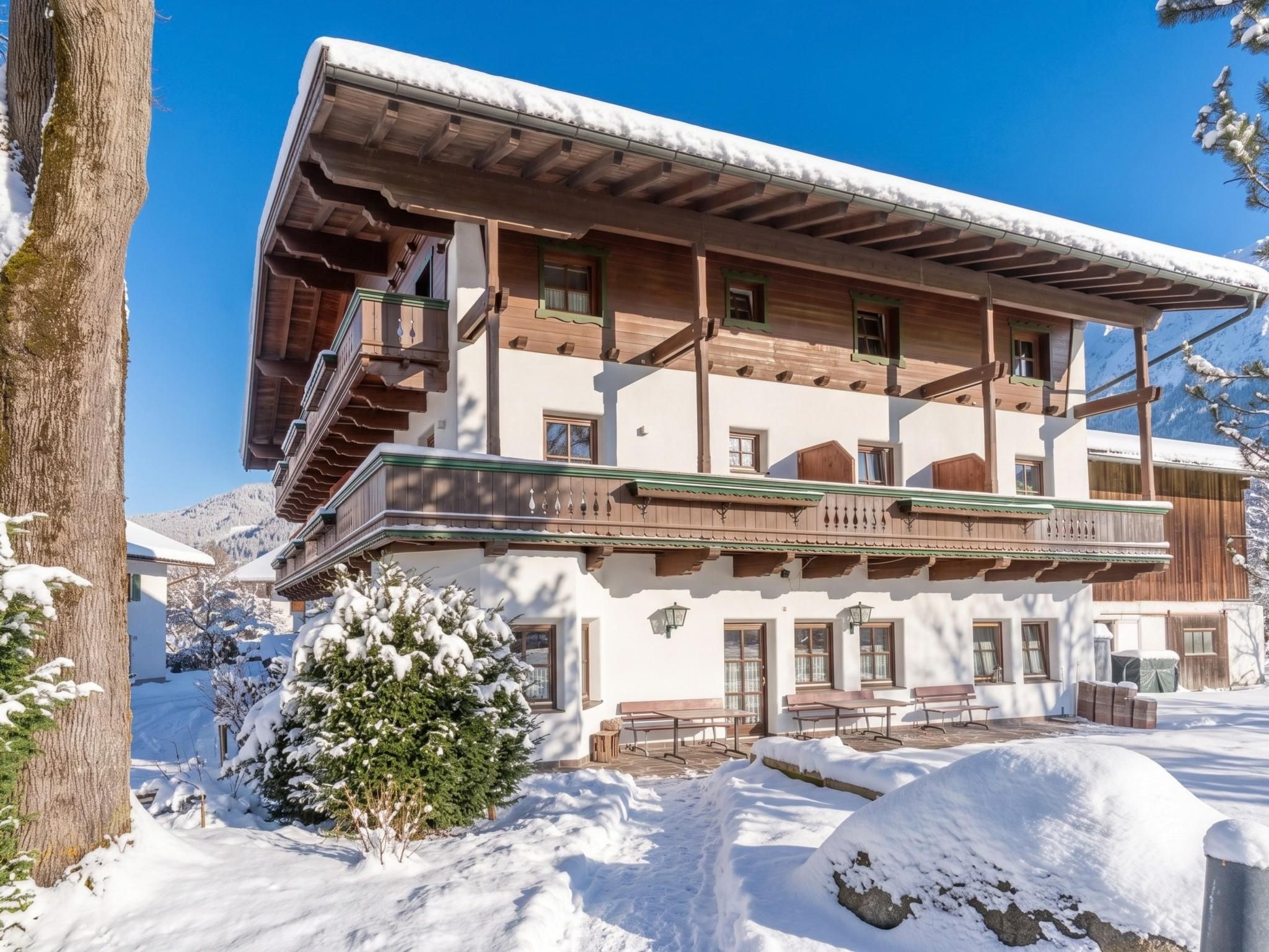 A two-story building with a balcony, snow-covered surroundings, and a clear blue sky.