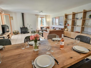 A dining area with a wooden table set for four, a bottle of wine, and a vase of flowers. - Villa with private pool and vineyard views (Beaufort)