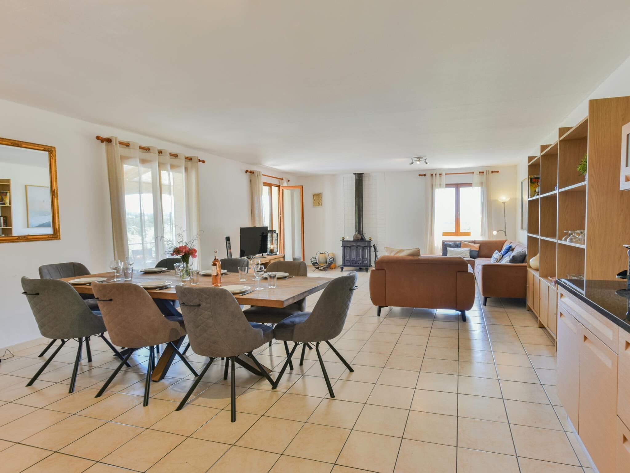 Amplia sala de estar con una mesa de comedor, sillas, un sofá y una zona de cocina con armarios de madera y una estufa.