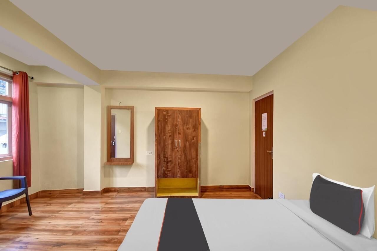 A hotel room with a bed, wooden wardrobe, and a mirror.