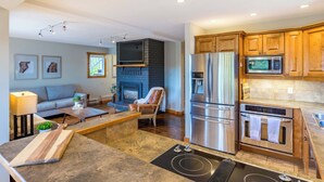 A modern kitchen with a built-in stove, stainless steel appliances, and wooden cabinets. - The Alpine | Sleeps 10 | Perfect for Large Groups! (Vernon)
