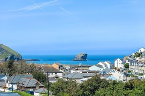 Un pueblo costero con casas, una destacada formación rocosa y una vista despejada del mar.