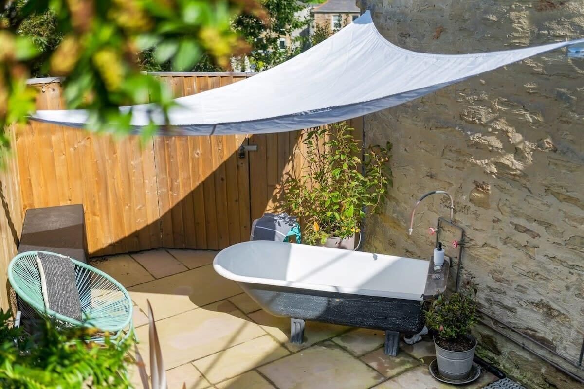 Une salle de bain avec une baignoire sur pieds, une clôture en bois et des plantes en pot.