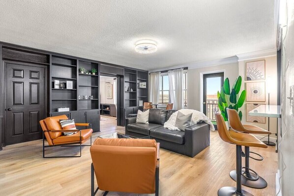 A modern living room with a sofa, two armchairs, a coffee table, and a bookshelf. - Luxe Living~ Free Parking! (Atlanta)