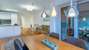 A modern kitchen with white cabinets, a wooden dining table with four chairs, and pendant lights. - Seeblick alpe maritima Ski & See-Top 12 by Interhome (Ossiacher See)