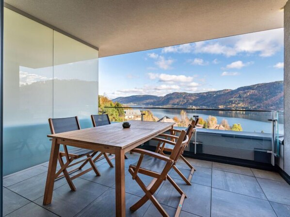 Enjoy a meal with a view of the lake and surrounding hills from this dining area with a large table and six chairs.
