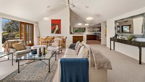 A spacious living room with a large sofa, a coffee table, and a dining area with chairs and a table.