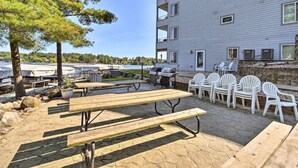 Une terrasse extérieure avec des tables et des chaises pour pique-nique, un barbecue et une vue sur une marina remplie de bateaux.