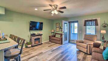 A living room with a fireplace, a television mounted on the wall, and a ceiling fan.