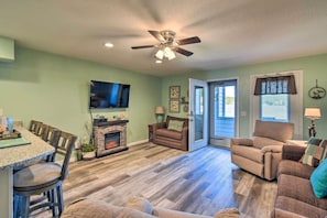 A living room with a fireplace, a television mounted on the wall, and a ceiling fan. - Ethel's Beachfront Retreat (Wisconsin Dells)