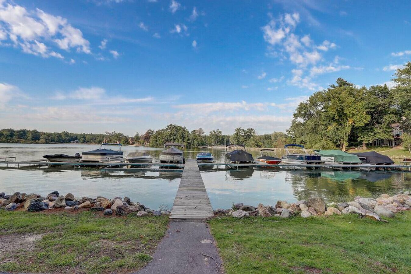 A dock with boats, a clear sky, and trees in the background.