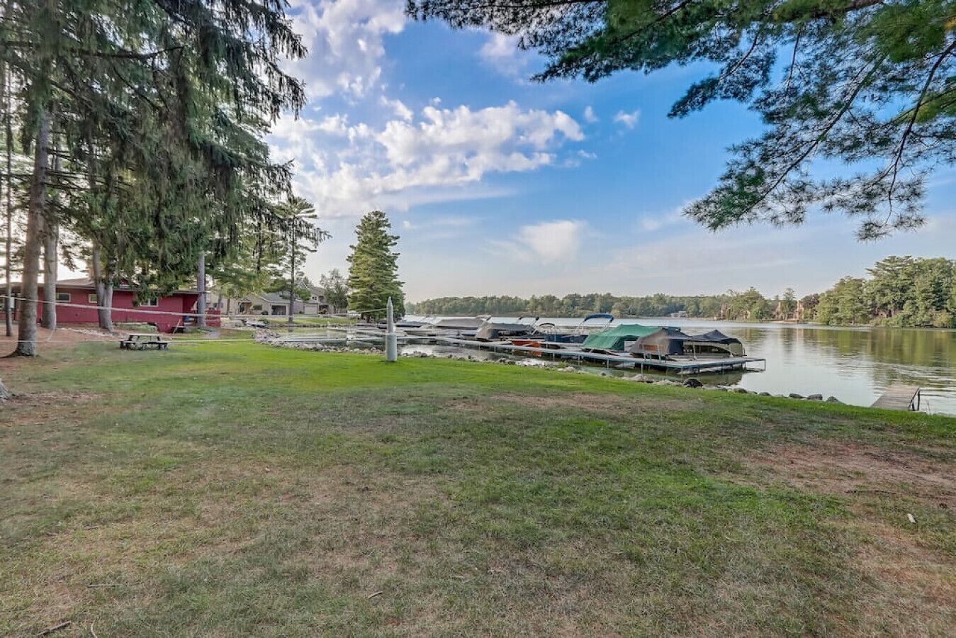 A lakeside property with a dock, boats, and a grassy area.