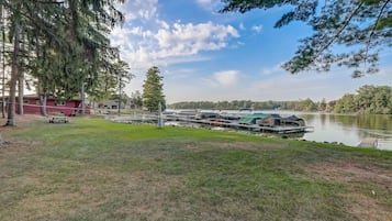 A lakeside property with a dock, boats, and a grassy area.