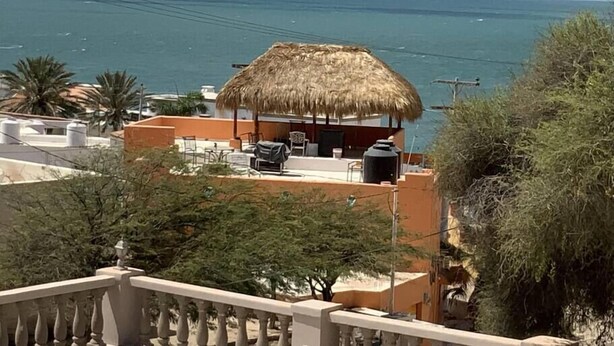 Ein Küstenanwesen mit einer überdachten Sitzgelegenheit, die auf das Meer blickt.