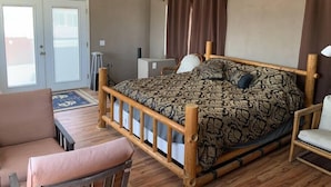 Ein Schlafzimmer mit einem hölzernen Bett, einem Sessel, einem Schreibtisch und einem Deckenventilator.