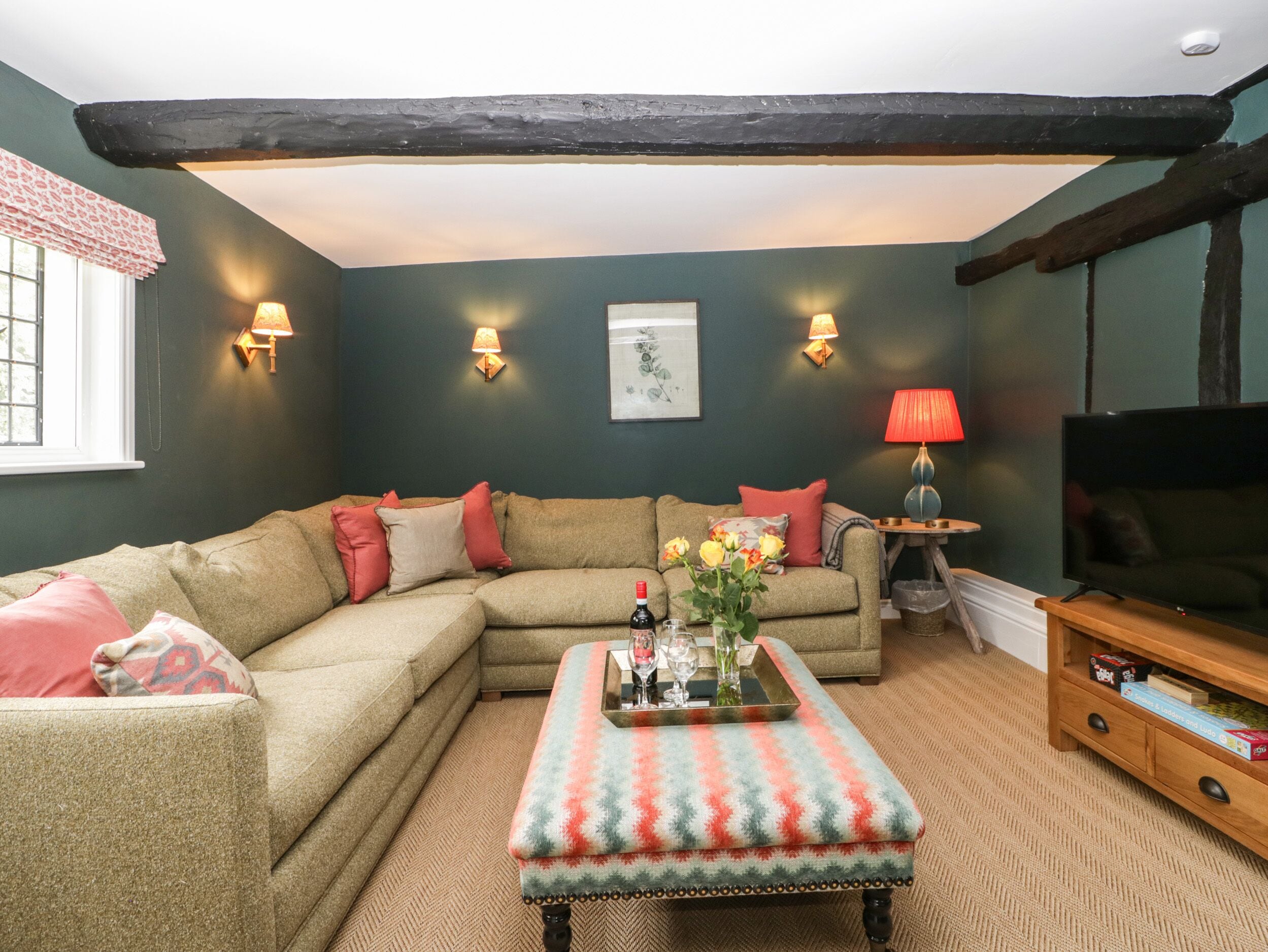A cozy living room with a sectional sofa, a matching ottoman, and a television.