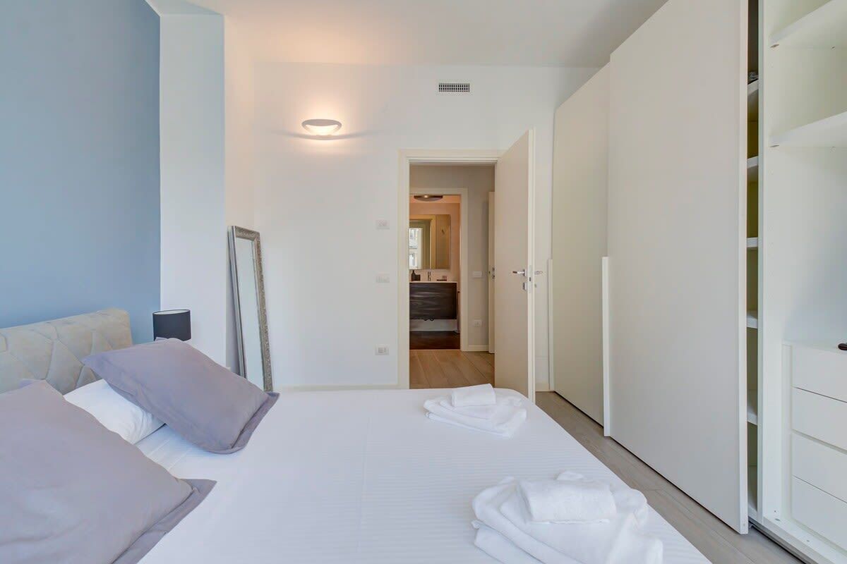 Una habitación de hotel con una cama, un armario y un baño visible a través de una puerta abierta.