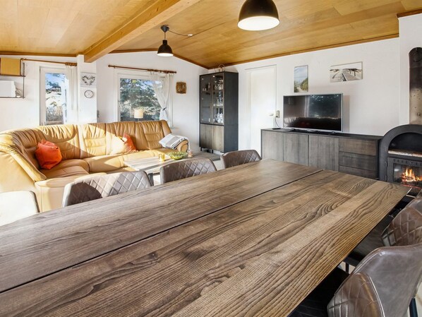 A cozy living area with a wooden dining table, leather sofa, and a fireplace.