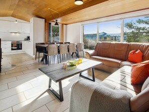 A modern interior with a dining area, sofa, and kitchen.