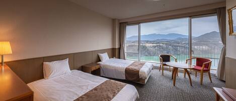 Une chambre d’hôtel avec deux lits, un bureau, une chaise et une vue sur les montagnes et un pont.