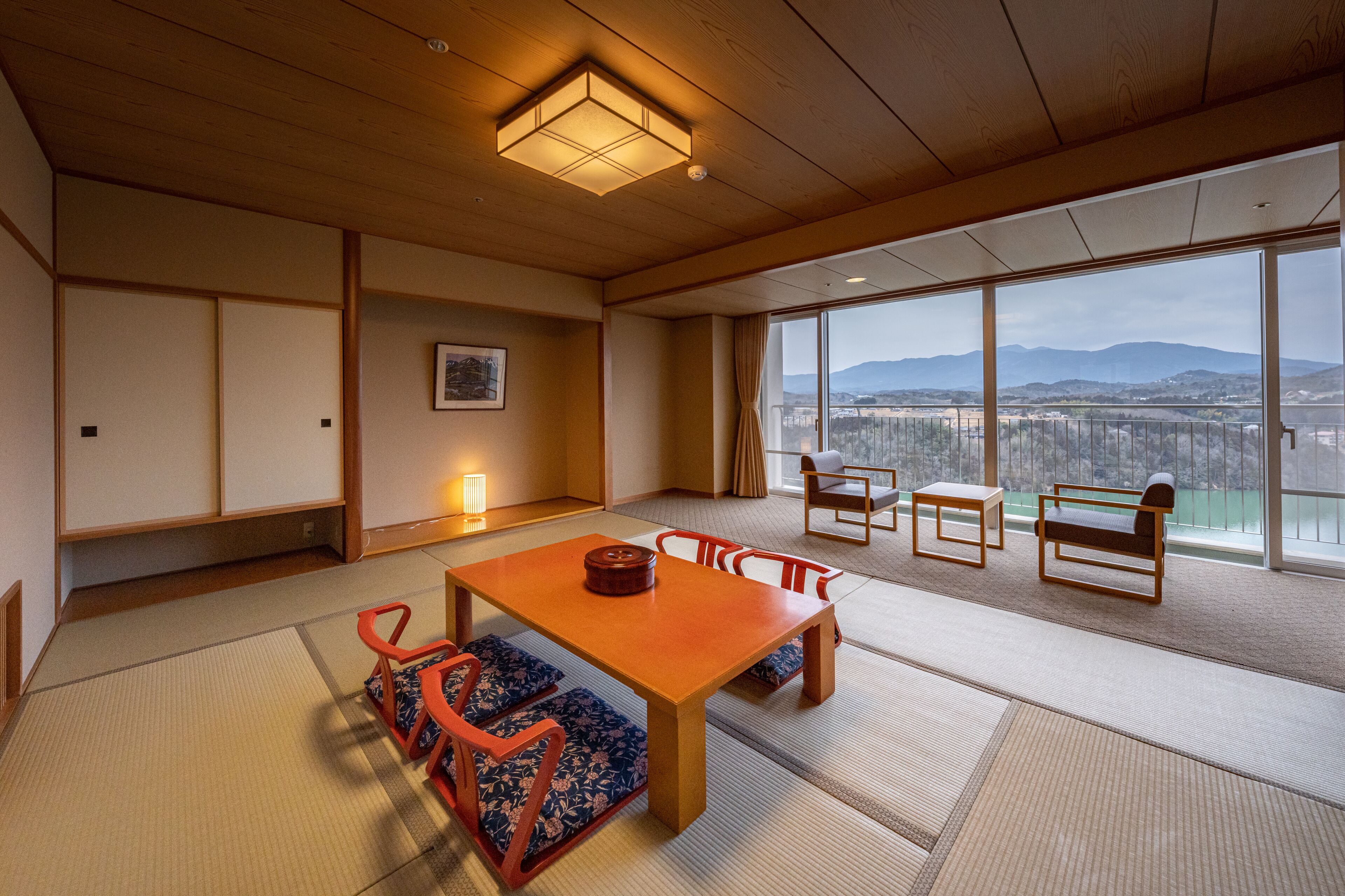 Ein traditioneller japanischer Raum mit Tatami-Böden, einem niedrigen Holztisch und Blick auf eine Stadtlandschaft durch große Fenster.