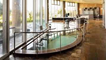 A spa area with a circular hot tub, glass railings, and a view of the outdoors.