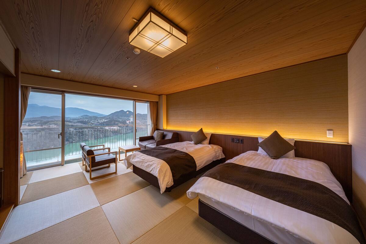 Habitación de hotel con dos camas, un balcón y vistas a montañas, además de techo de madera.