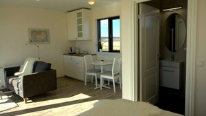 A compact bedroom with a large bed, a small kitchenette, a dining area, and a bathroom with a mirror. - Cottages built for privacy and unobstructed views (Bláskógabyggð)