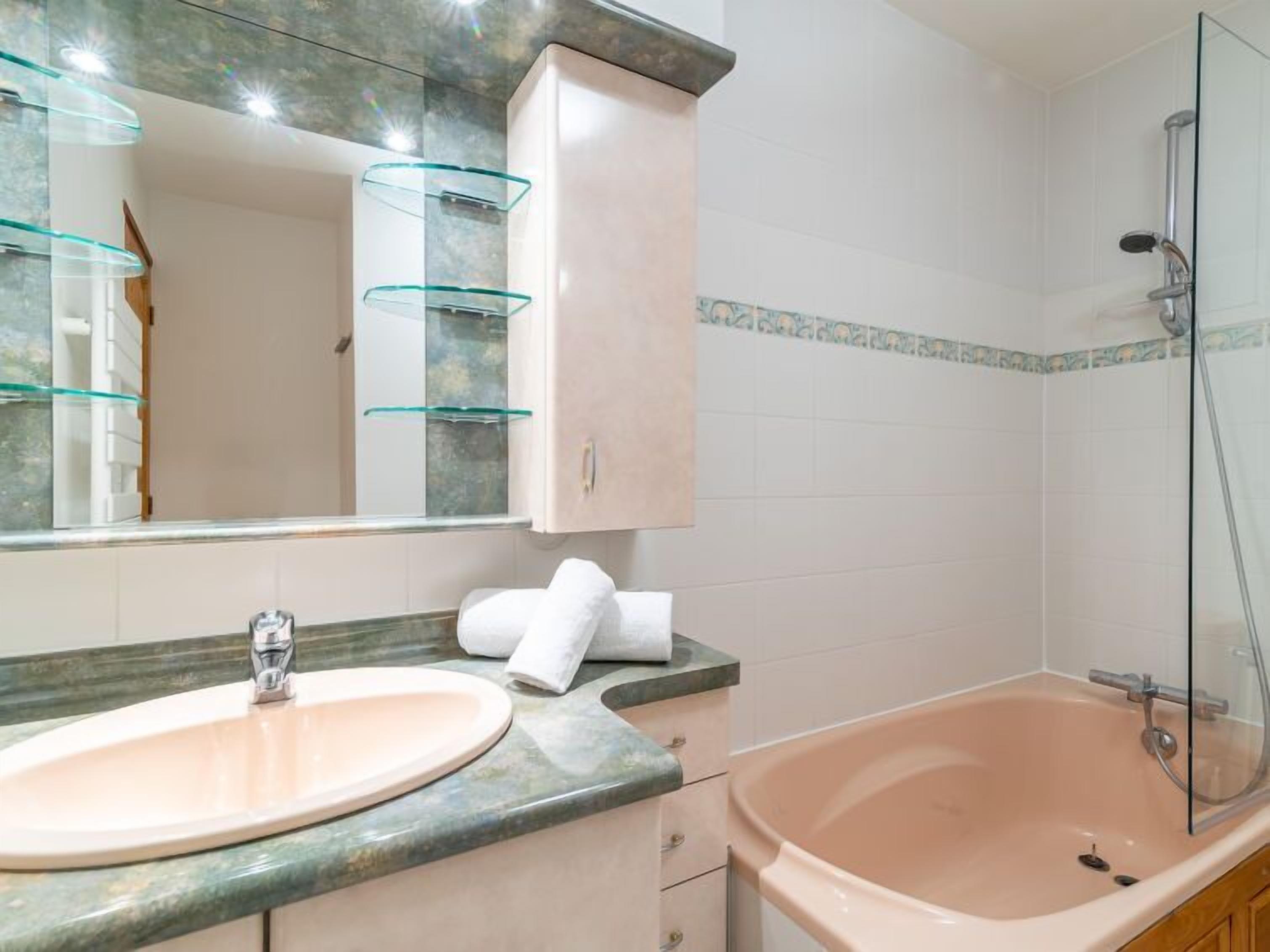 A bathroom with a sink, mirror, cabinet, and bathtub.