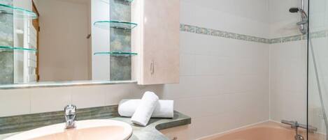 A bathroom with a sink, mirror, cabinet, and bathtub.