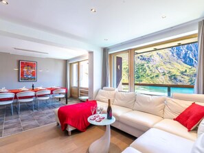Relax in a spacious room with a scenic mountain view, a comfortable sofa, and a dining area perfect for socializing.