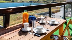 A wooden table set for breakfast with a scenic mountain and lake view.