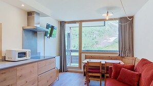 A modern kitchen with wooden cabinets, a microwave, and a large window overlooking a scenic landscape. - Home Club (Lavachet) by Interhome (Tignes)