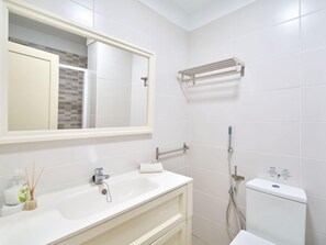 Ein modernes Badezimmer mit großem Spiegel, Waschbecken, Handtuchhalter und Toilette.