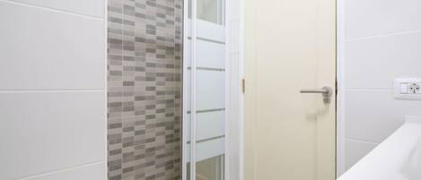 A bathroom with a shower, a toilet, and a sink.