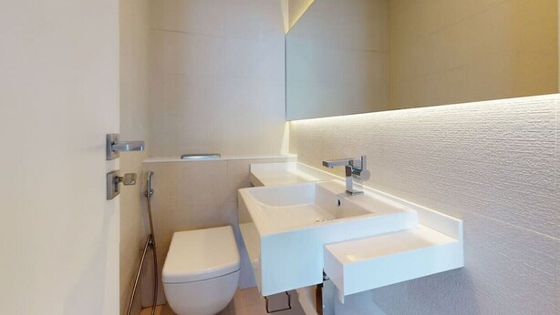 Un baño moderno con lavamanos, espejo y retrete blancos.