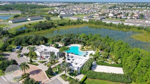 A residential area with a large swimming pool surrounded by lush greenery and a lake. - 1052 3BR Luxury Resort House by Disney Orlando (Davenport)
