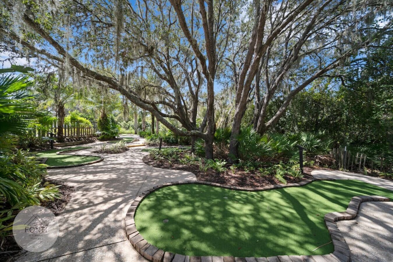 A golf course with a winding path, surrounded by mature trees and lush greenery.