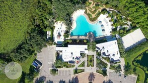 An aerial view of a resort with a large swimming pool, multiple guest rooms, and lush surrounding greenery. - 1052 3BR Luxury Resort House by Disney Orlando (Davenport)