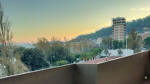 Ein Balkon mit Blick auf eine Stadtlandschaft im Abendrot.