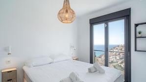 Un dormitorio moderno con una cama grande, vistas de la ciudad y una lámpara colgante de mimbre.