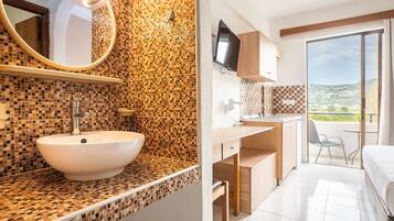 Une salle de bain avec un mur recouvert de mosaïques, un lavabo et un miroir.