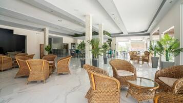 A spacious lobby with wicker furniture, a marble floor, and large windows allowing natural light.