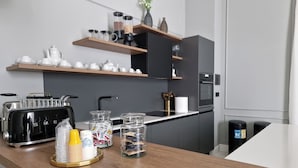Una cocina moderna con encimera de madera, tostadora, frascos de vidrio y cafetera.