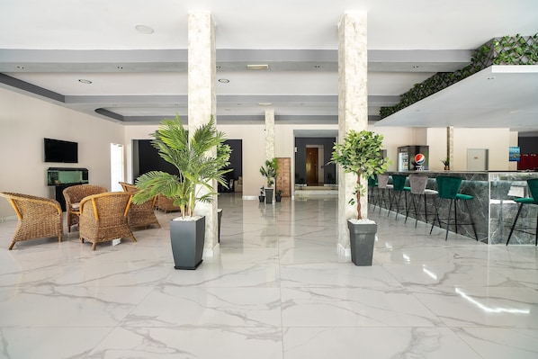 A lobby with a reception desk, seating area, and a staircase.